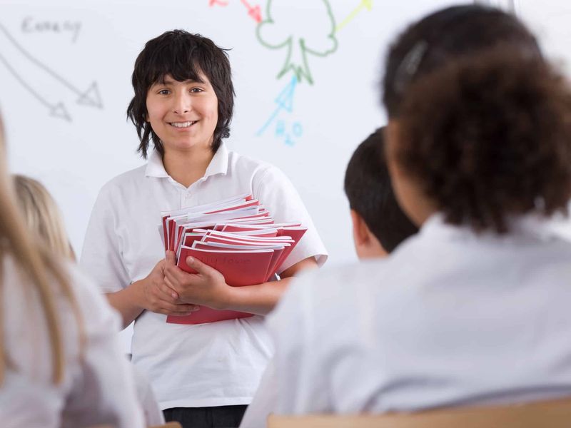 Student handing out printed workbooks in class
