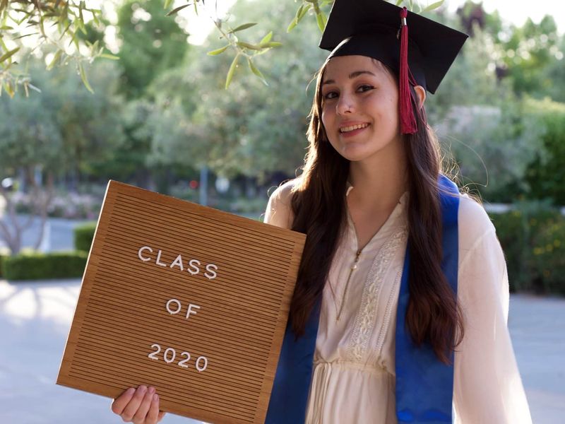 Graduate celebrating with her class-year sign on presentation day
